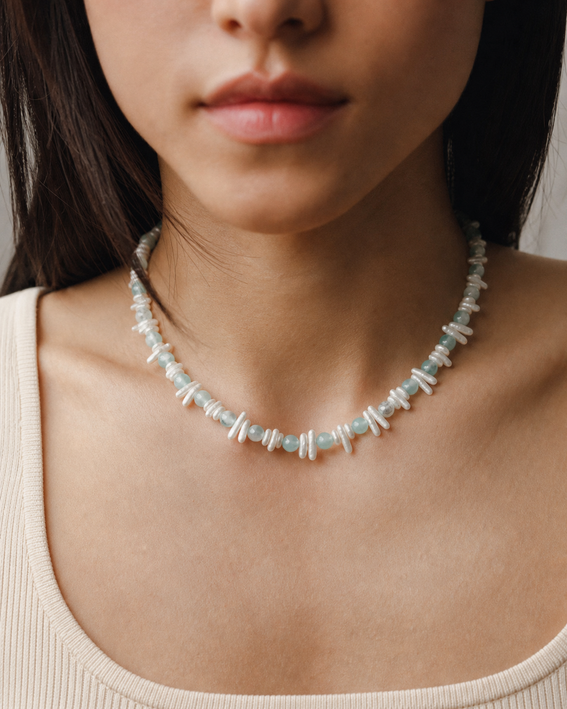 Model wearing layered gemstone necklaces